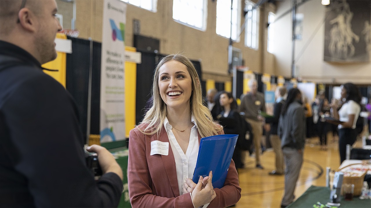 Students actively engaging with recruiters at a career fair booth, showcasing resume and practicing professional communication, highlighting Mizzou Career Tools for student career development.