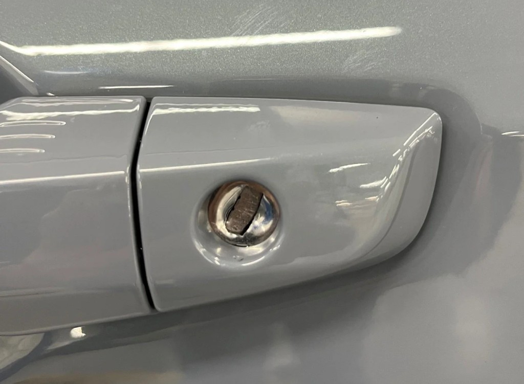 Close-up of car door handle, potential theft mark visible.