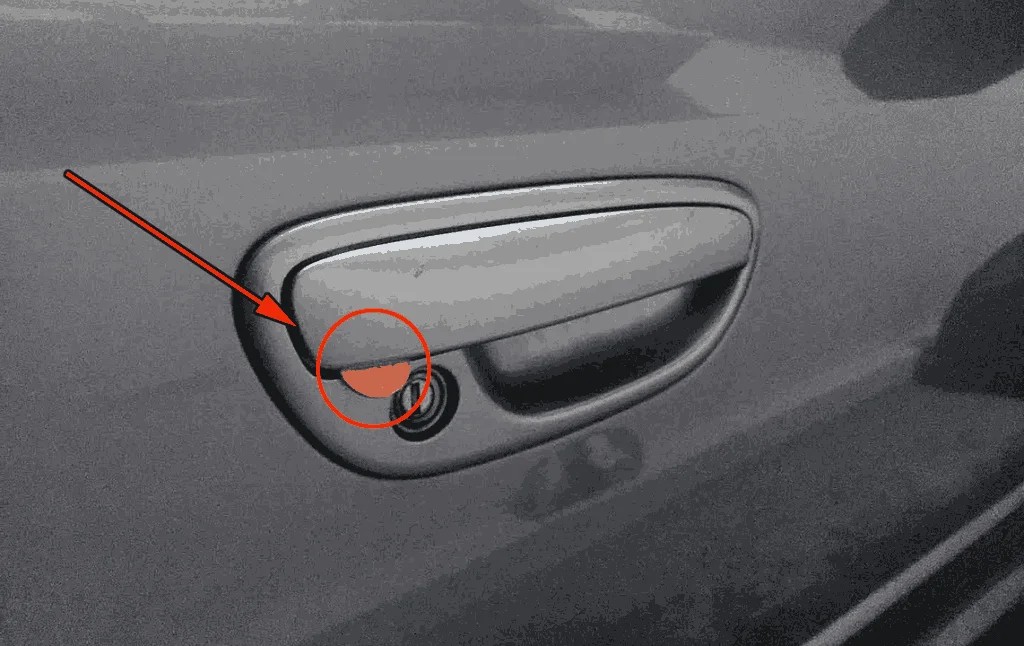 Close-up of car door handle with suspicious orange mark, sign of potential car theft.