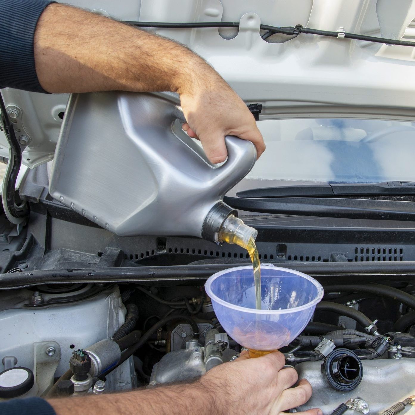 Pouring fresh oil into car engine for maintenance