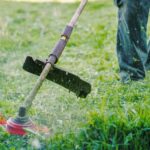 Close up on string trimmer head weed cutter petrol or electric brushcutter working in the yard or field cutting grass in garden in day low angle view