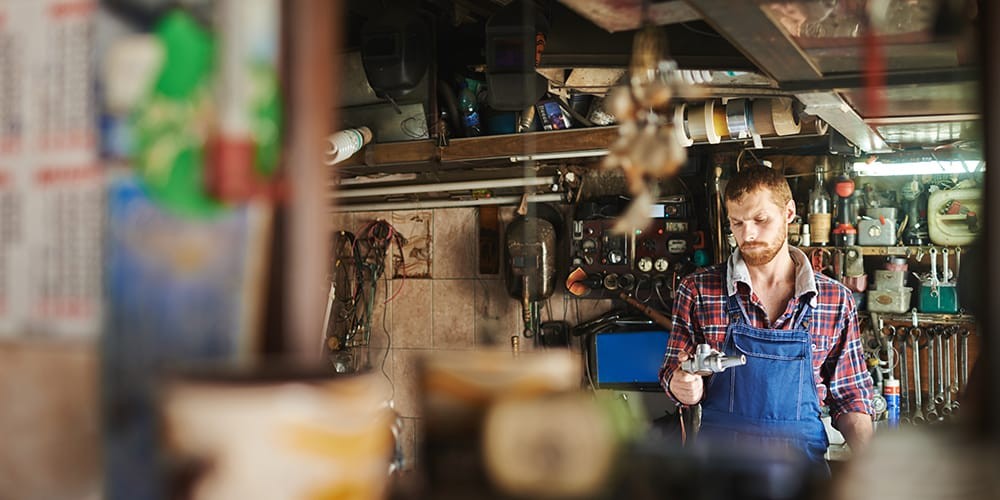 Professional mechanic thoughtfully selects a tool from a well-organized toolbox