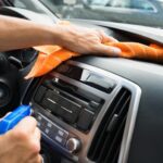 Vacuuming car dashboard to remove dust and debris