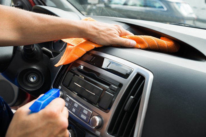 Vacuuming car dashboard to remove dust and debris