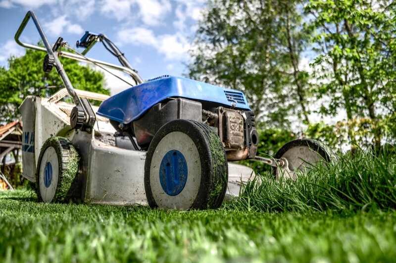 Modern lawn mower cutting grass in a sunny garden