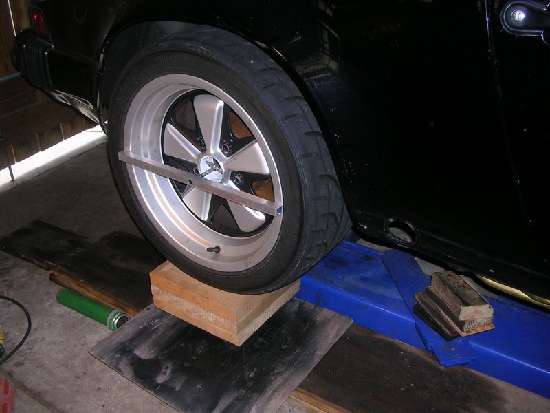 alt text: Aluminum mounting bar attached to a wheel for alignment.