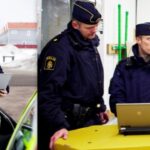 alt text: A police officer standing next to a police car