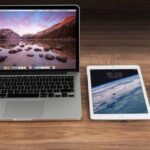 laptop, tablet, and iphone sitting on wooden desk