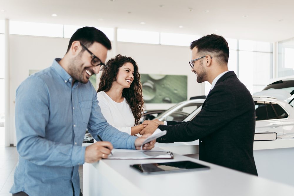 Modern car dealership showroom with salespeople and customers