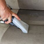 alt text: a person vacuuming dog hair from a car seat